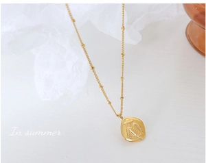 Macro view of French vintage gold necklace featuring person relief coin and bead chain