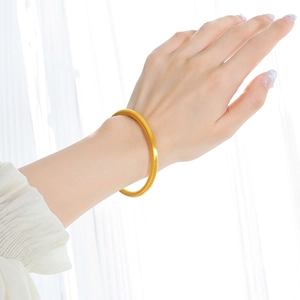 Minimalist 18K gold plated titanium steel bangle with matte finish on female model
