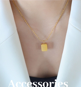 Close-up of a gold-plated geometric square pendant necklace with engraved details on a model