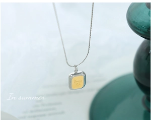 Macro d'un pendentif carré argenté avec gravure Smile dorée et motif de visage souriant