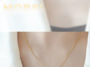 Close-up of a minimalist gold bead and cylinder link chain necklace on model's neck