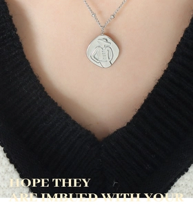 Macro shot of silver embossed portrait pendant on a sleek geometric link necklace