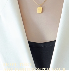 Macro shot of 18k gold plated rectangular charm with engraved text on a chain necklace