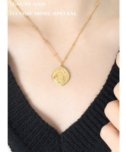 Close-up of golden portrait relief pendant on delicate beaded chain for women