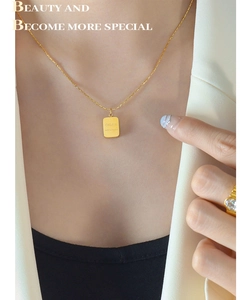 Close-up of golden geometric pendant necklace worn by a model in a white blazer