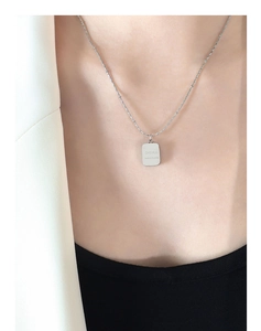 Detail of silver vertical bar pendant with CHARM engraving on a delicate beaded chain