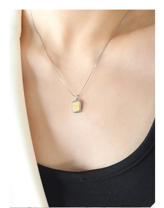 Gros plan d'un pendentif carré géométrique avec gravure Smile et tons or et argent