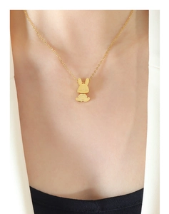 Gros plan d'un collier pendentif lapin mignon doré porté au cou d'une femme
