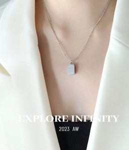 Detail of a square metal pendant with CHORA engraving on a beaded link necklace