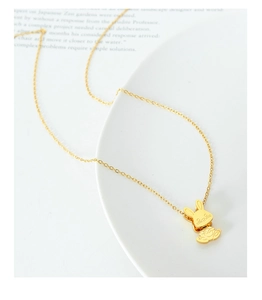 Gros plan d'un collier avec pendentif lapin doré et détails fins sur une assiette