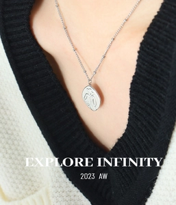 Silver bead chain necklace with artistic line-art female silhouette pendant on a cardigan