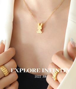 Gros plan d'un collier pendentif lapin doré et d'une bague texturée assortie sur mannequin