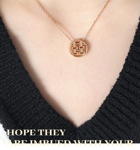 Detail of rose gold titanium necklace featuring a hollow double happiness pendant on model