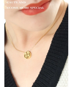 Close-up of gold hollow Double Happiness pendant necklace worn on a woman neck