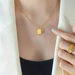 Gold stainless steel rectangle charm necklace and textured ring on elegant female model