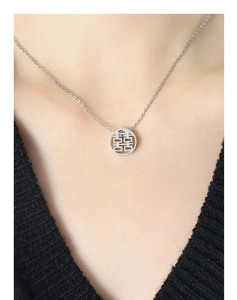 Close-up of a silver stainless steel necklace with a hollow Double Happiness pendant