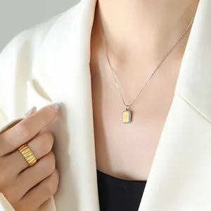 Collier chic en argent avec pendentif rectangle et bague dorée sur un mannequin