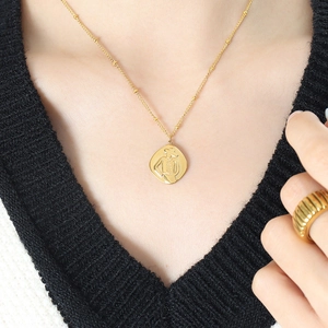 French relief portrait necklace and textured gold ring set on a knit V-neck model