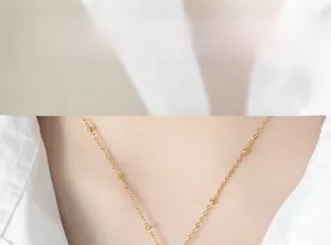 Minimalist gold thin chain necklace with beads shown on a model neck with white shirt