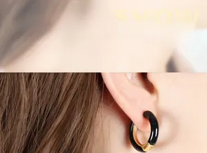 Close-up of chunky black and gold enamel hoop earring worn by a model for size