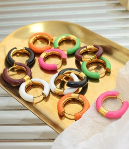 Detailed close-up of colorful enamel hoop earrings on a gold tray with luxury aesthetic