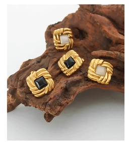 Detail of square vintage gold earrings with black and white stone inlays on wood