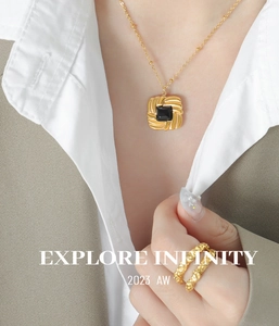Detail of gold chain necklace with black gemstone pendant and hammered texture ring
