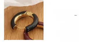Detailed macro view of C-shaped chunky enamel hoop earrings in burgundy and black tones