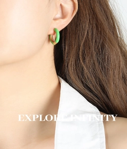 Close-up of green enamel and gold plated C-shape hoop earring worn by a model