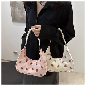 Detail of corduroy underarm bag with strawberry print and decorative pearl handle strap