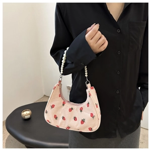 Detail of pink corduroy shoulder bag featuring strawberry prints and pearl chain handle