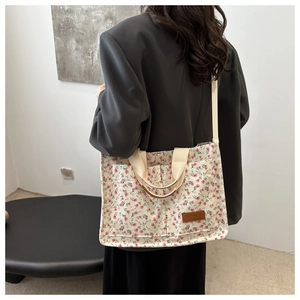 Detail view of floral canvas tote bag with dual front pockets and brown leather patch