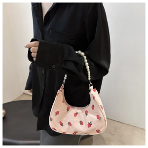 Detailed shot of pink corduroy shoulder bag featuring strawberry print and pearl handle