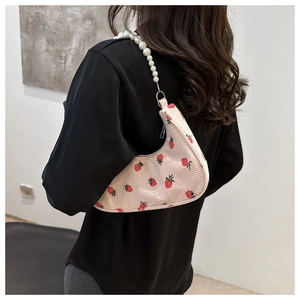 Detail of strawberry print corduroy bag featuring elegant pearl bead shoulder strap