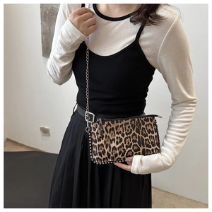 Detail of leopard print handbag featuring silver studs and a metallic chain strap
