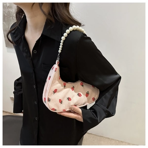 Detailed view of pink corduroy saddle bag with strawberry print and pearl chain strap