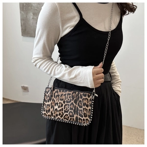 Detail of leopard print shoulder bag with silver studs and metal chain strap on model