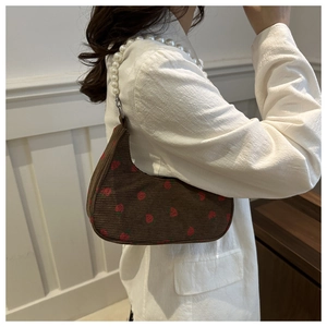 Detail of brown corduroy baguette bag with strawberry print and pearl chain strap
