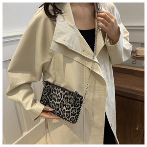 Detail of trendy leopard print shoulder bag with silver chain strap on khaki trench coat
