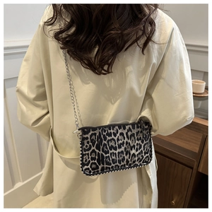 Detail of leopard print crossbody bag featuring silver bead trim and a sleek chain strap