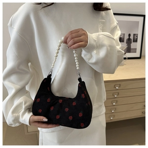 Detail of corduroy bag with strawberry embroidery and pearl handle shown with white hoodie
