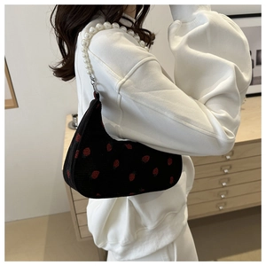 Detail of black corduroy shoulder bag with strawberry patterns and pearl strap