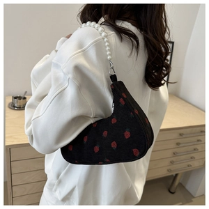 Detail of strawberry print corduroy crescent bag with elegant faux pearl handle strap