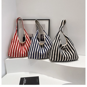 Détail de sacs hobo en toile rayée rouge, bleu et noir sur un support blanc élégant