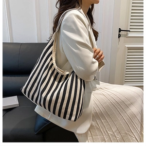 Sac fourre-tout en toile à rayures noires et blanches porté avec un costume crème chic