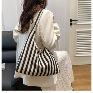Détail d'un sac cabas en toile à rayures verticales noires et blanches sur l'épaule du mannequin