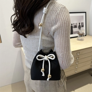 Minimalist black knit bucket bag with white cotton bow and gold bead details
