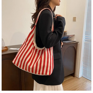 Vue latérale détaillée du grand sac cabas en toile à rayures rouges et blanches à l'épaule