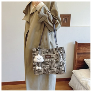 Detail of canvas tote bag with geometric stripes, leather handles, and plush cloud charm