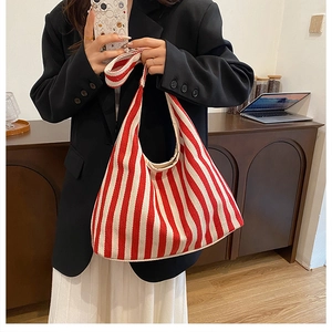 Détail d'un sac bandoulière en toile rayée rouge porté avec un blazer chic pour femme